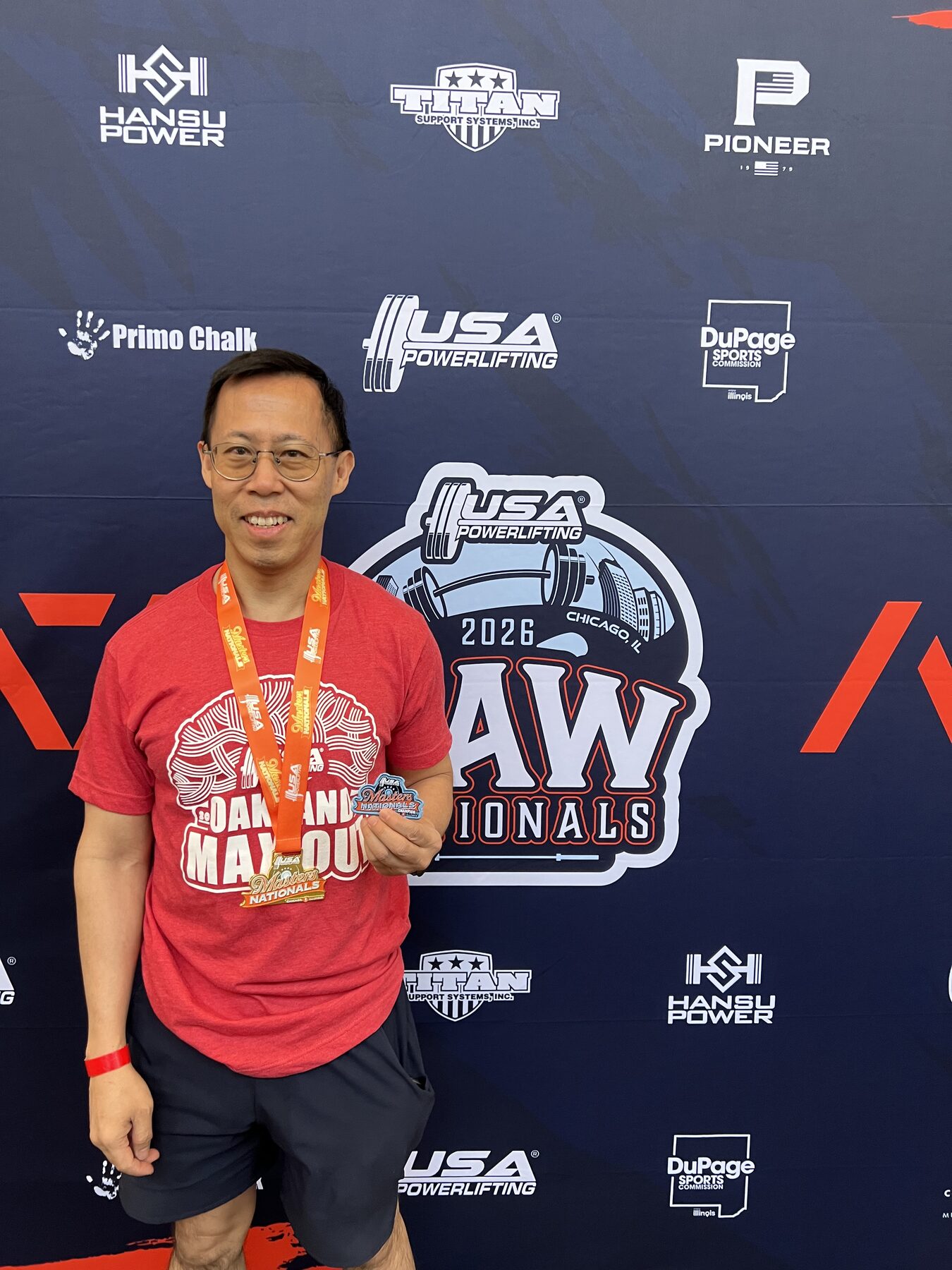 Roland Dong holding his USA Powerlifting medal